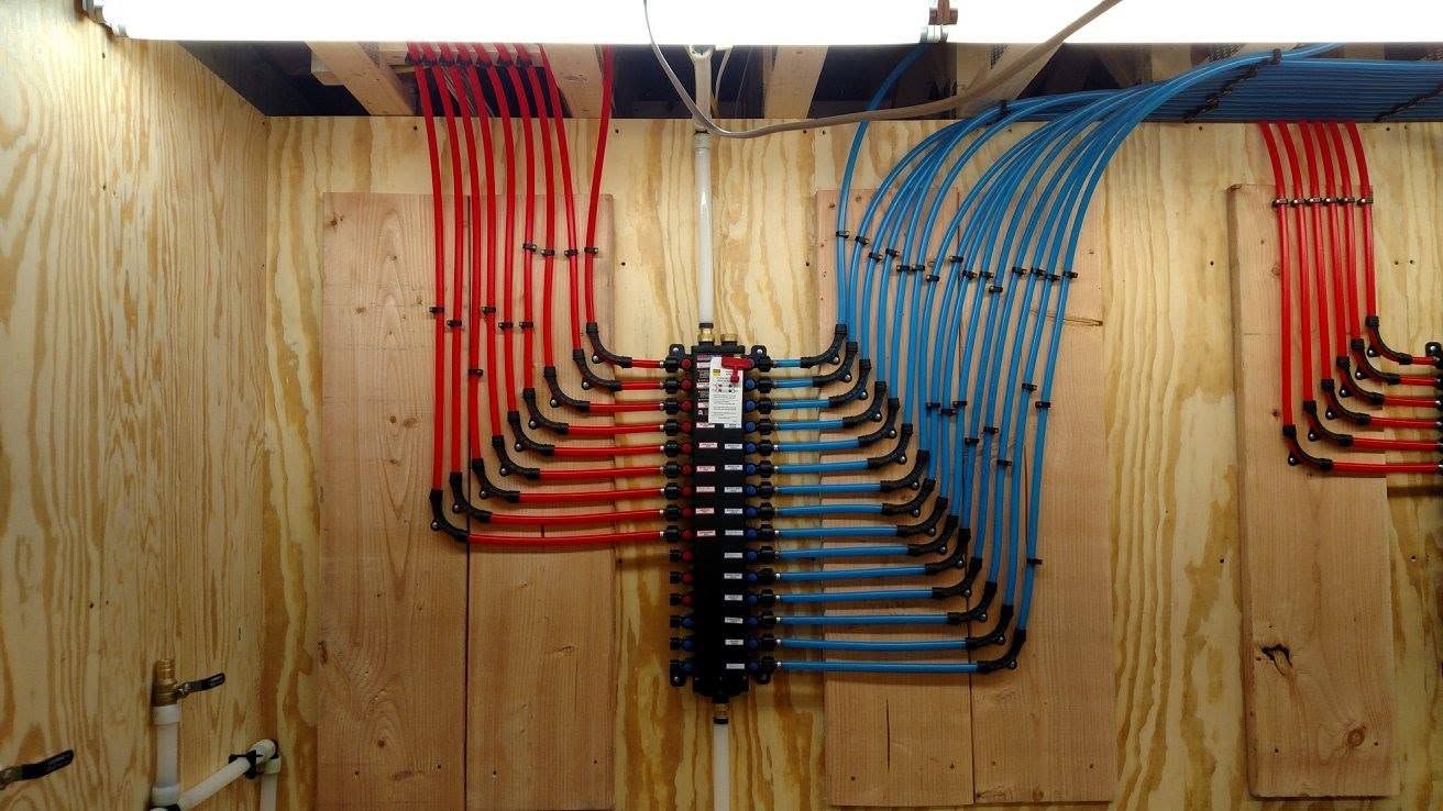 Color-coded electrical cables neatly routed across a plywood wall in a workshop or utility space