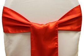 Red satin ribbon tied in a bow around a white chair back.