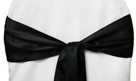 Black satin bow tied around a white garment or dress waist