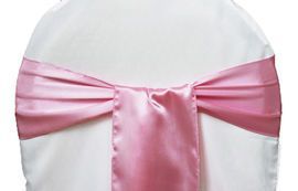 Pink satin chair sash tied in a bow on a white chair cover
