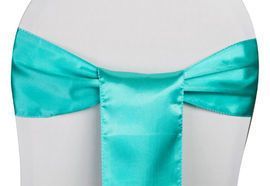 Turquoise satin ribbon bow tied around a white chair back