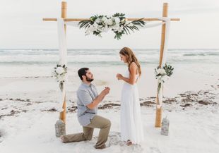 Beach wedding setup with white chairs, starfish aisle, and floral arch facing the ocean