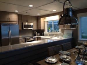 Modern kitchen with stainless steel appliances, granite island, pendant light, and large windows