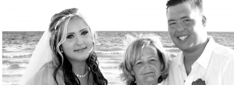 Three people smiling at the beach with ocean waves in the background