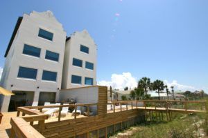Modern white building with large windows and a wooden deck under a clear blue sky