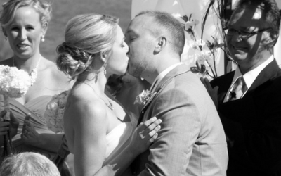 Newlyweds kissing at a wedding, with guests watching nearby