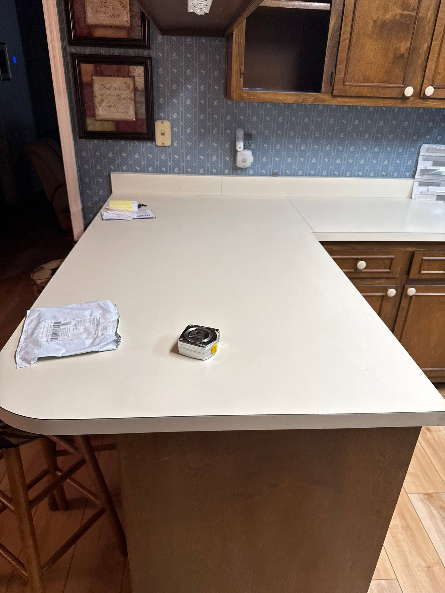 Kitchen island with white countertop, wooden cabinets, and a few small items on the surface.
