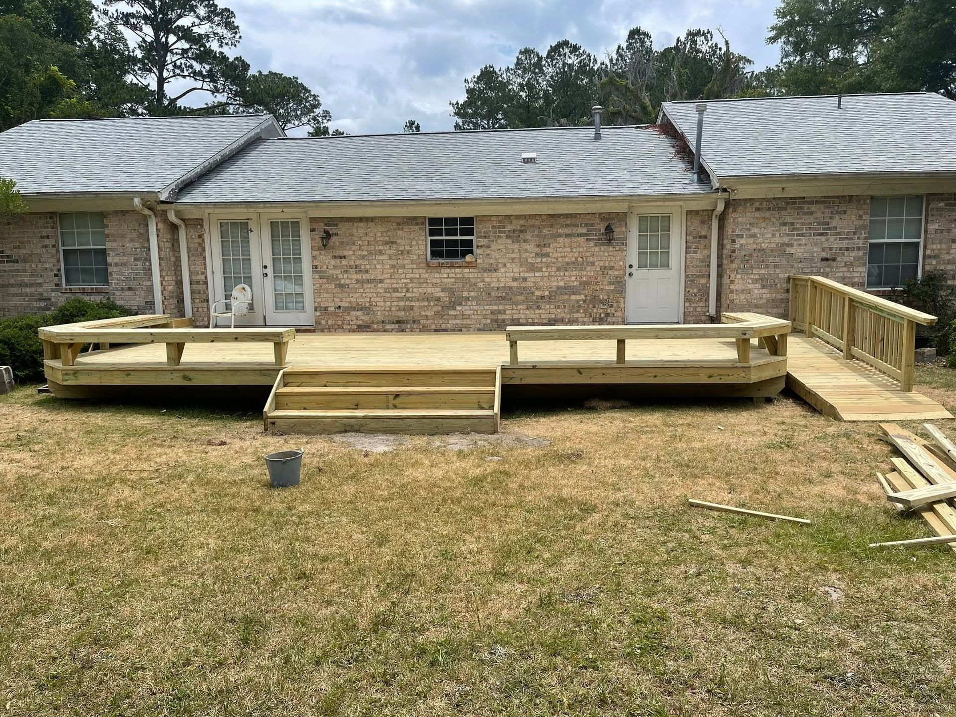 Backyard wooden accessibility ramp and platform leading to a brick house’s back door