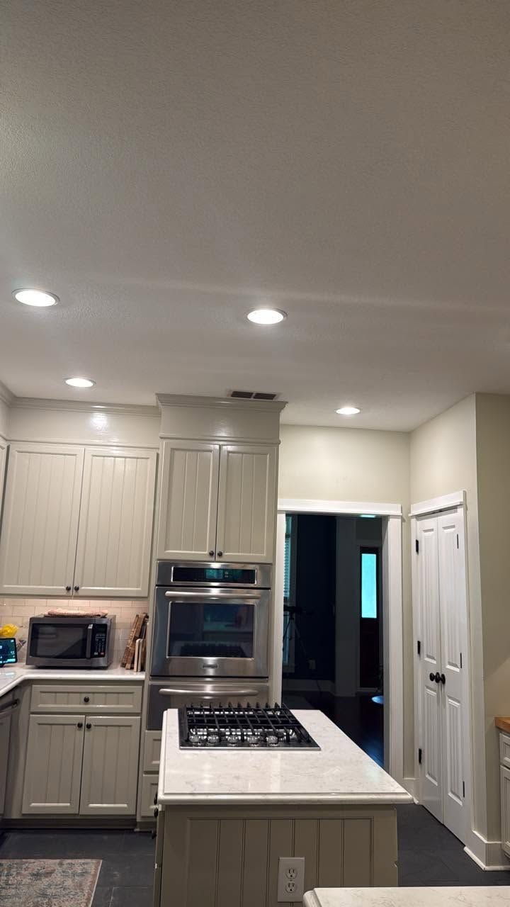 Bright kitchen with white cabinets, island, built-in oven, and recessed ceiling lights
