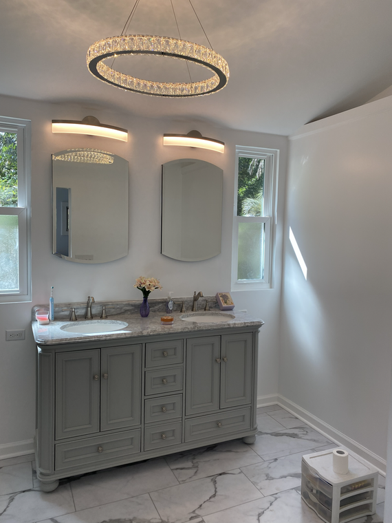Bathroom vanity with three mirrors, marble countertop, circular light fixtures, and a small step stool on the floor