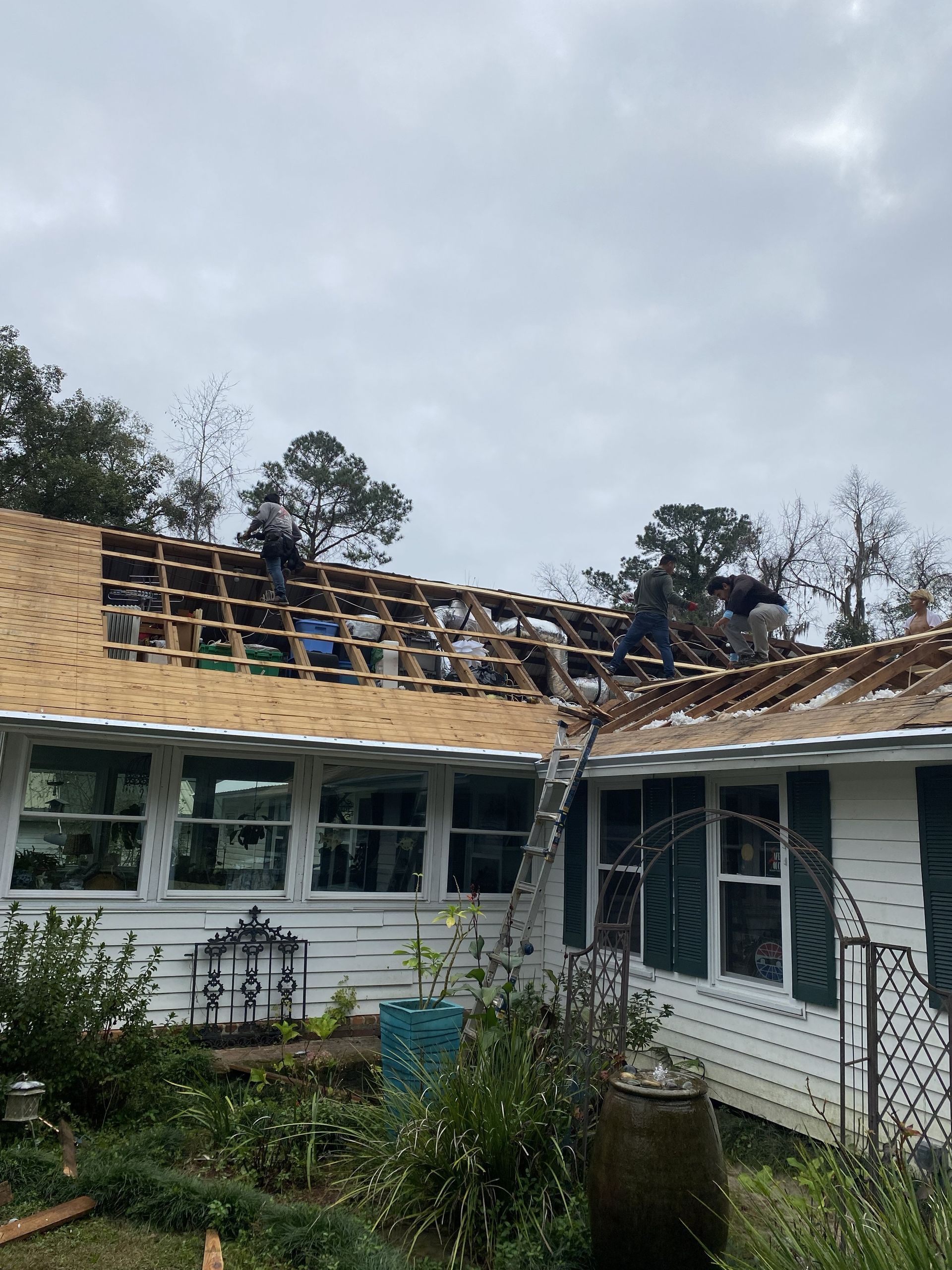 Storm-damaged house roof with exposed beams and debris after severe weather