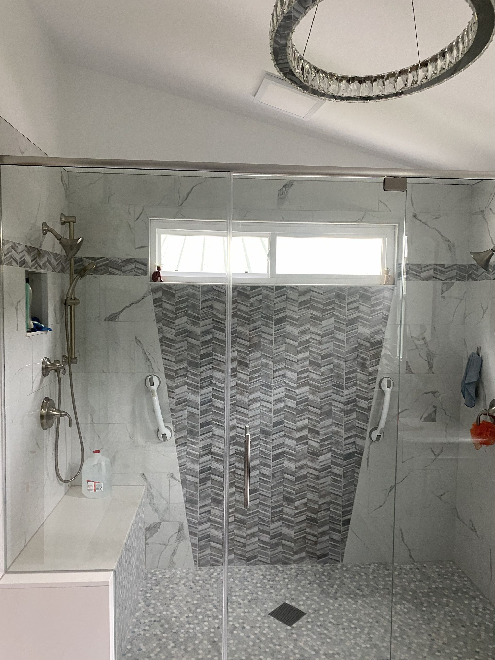 Partially tiled shower with gray stone accent wall and white walls, under renovation