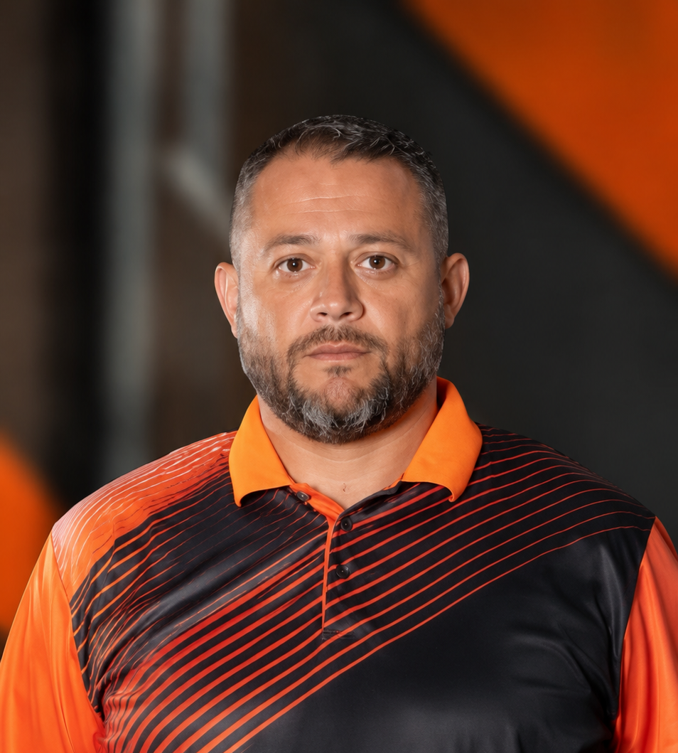 Portrait of a man in an orange and black collared shirt against a blurred dark background