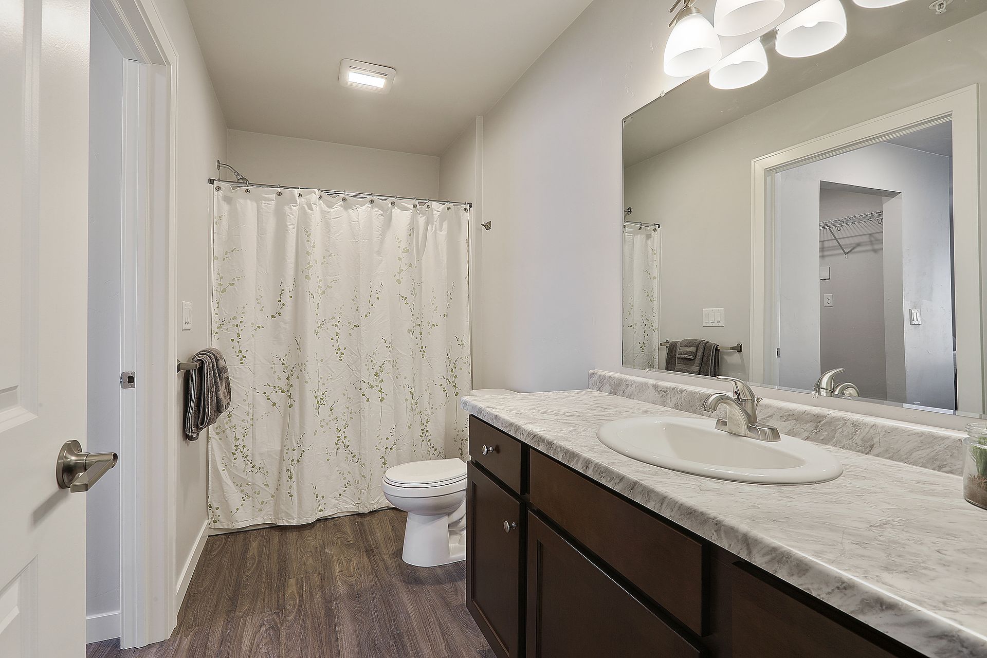 Modern bathroom with white shower curtain, dark wood vanity, marble countertop, and mirror
