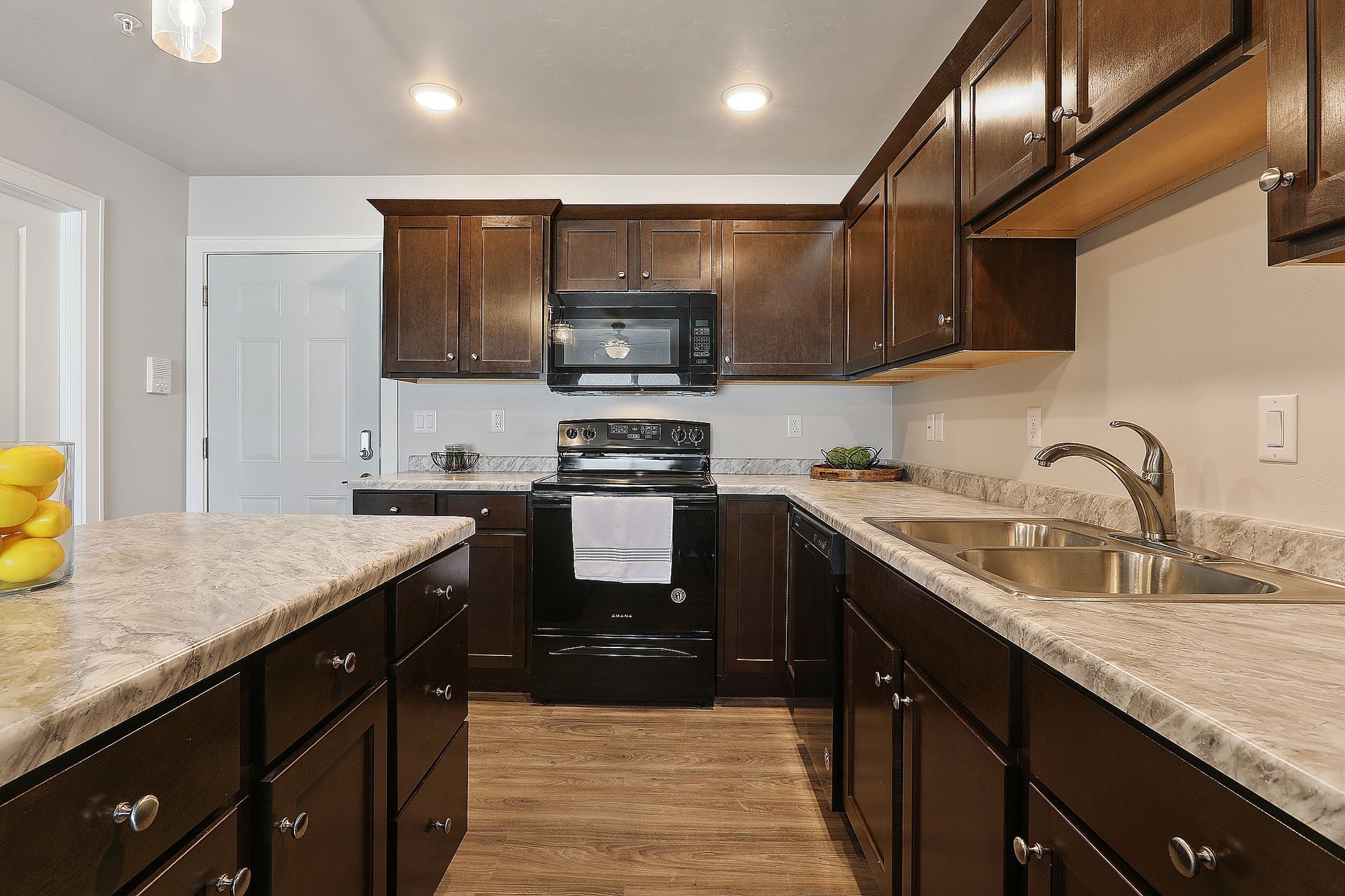 Modern kitchen with dark wood cabinets, granite countertops, and stainless steel appliances