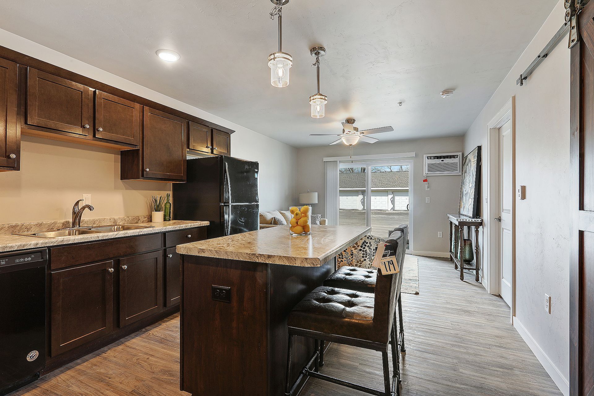 Modern kitchen with dark cabinets, granite island, bar stools, and pendant lights