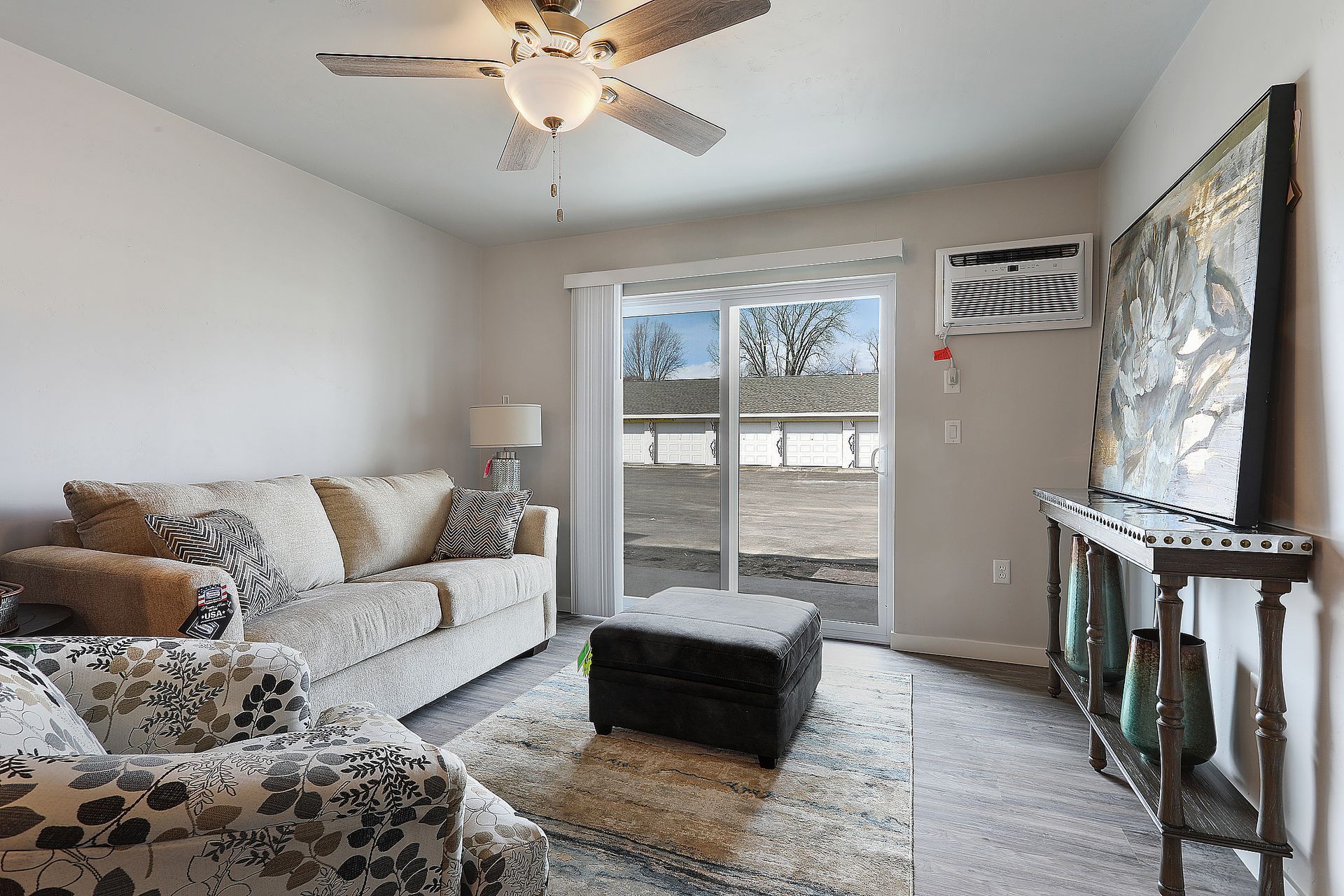 Bright living room with sectional sofa, ceiling fan, sliding glass doors, rug, and fireplace mantel