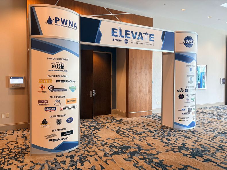 Conference entrance with “ELEVATE” banner and sponsor logos on white-and-blue archway.