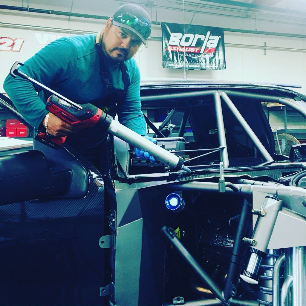 A man is working on a race car in a garage.