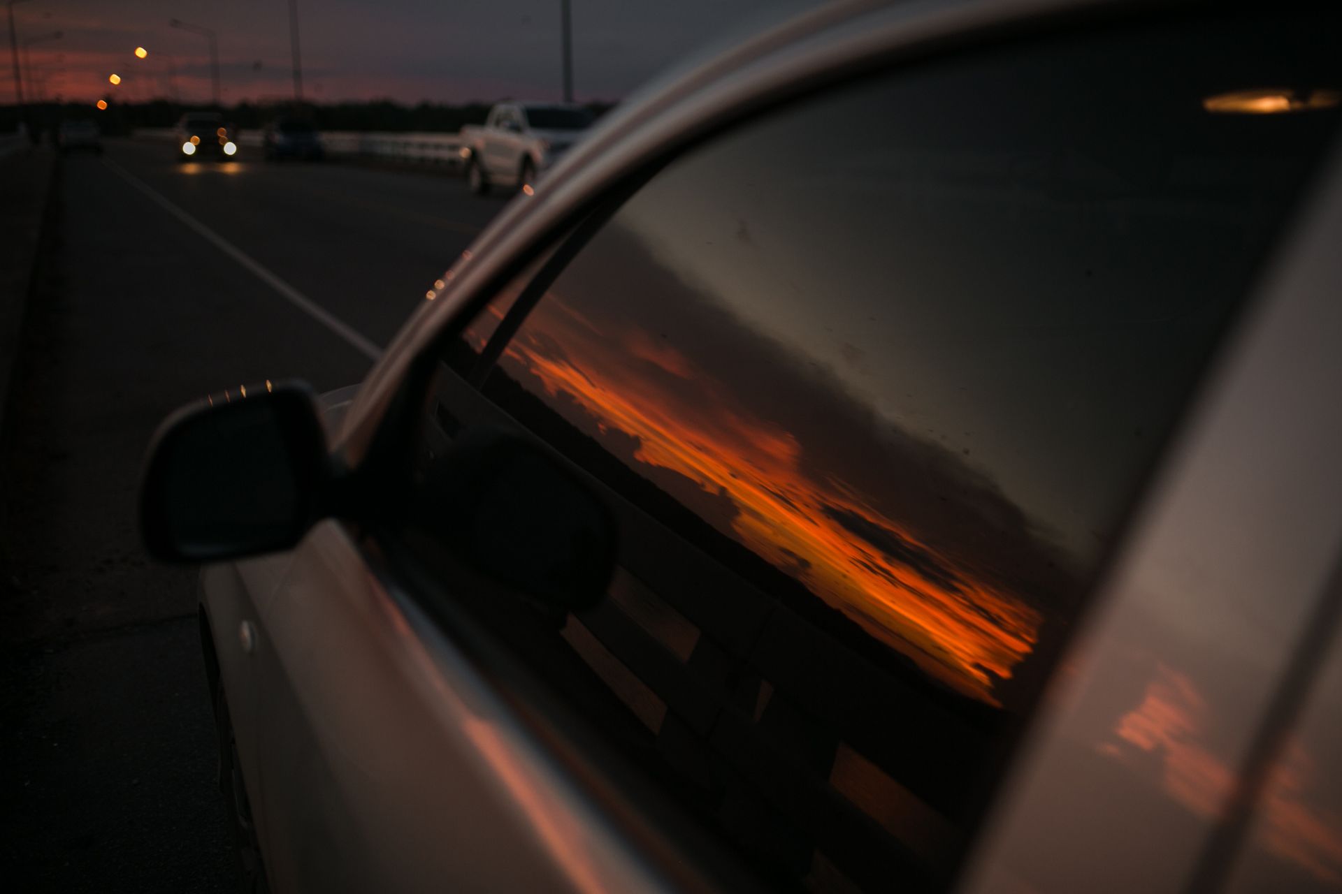 A Car Is Driving Down a Highway at Sunset. A Car Is Driving Down a Highway at Sunset.