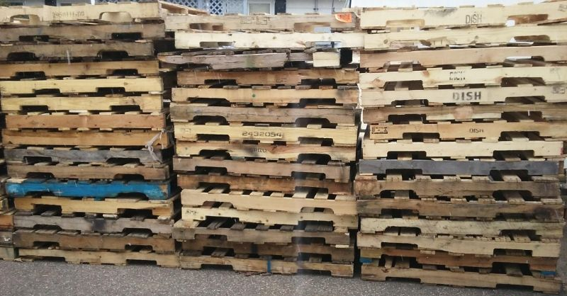 Stacks of wooden pallets piled in rows inside a warehouse or storage area.