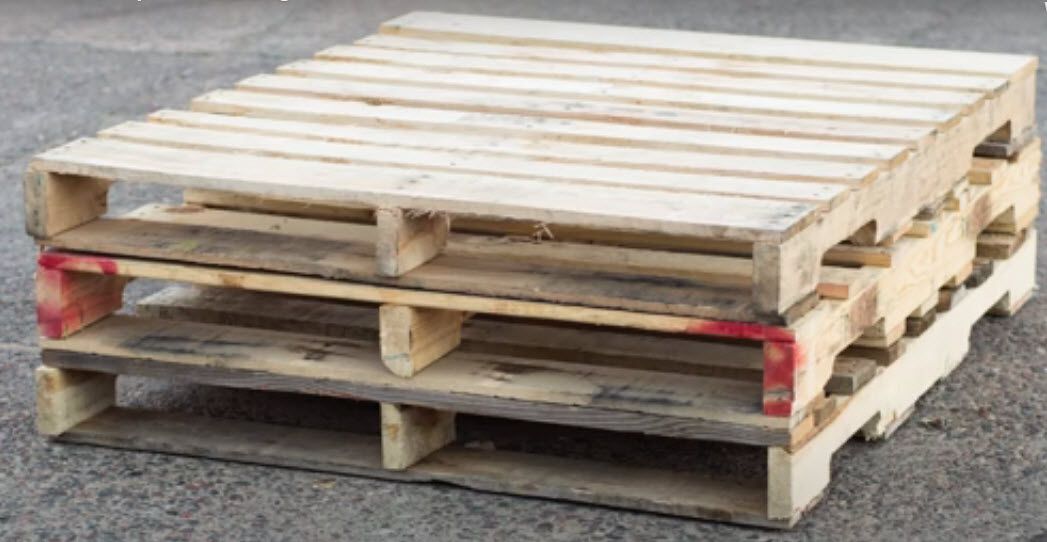 Stacked wooden shipping pallets on a concrete surface.