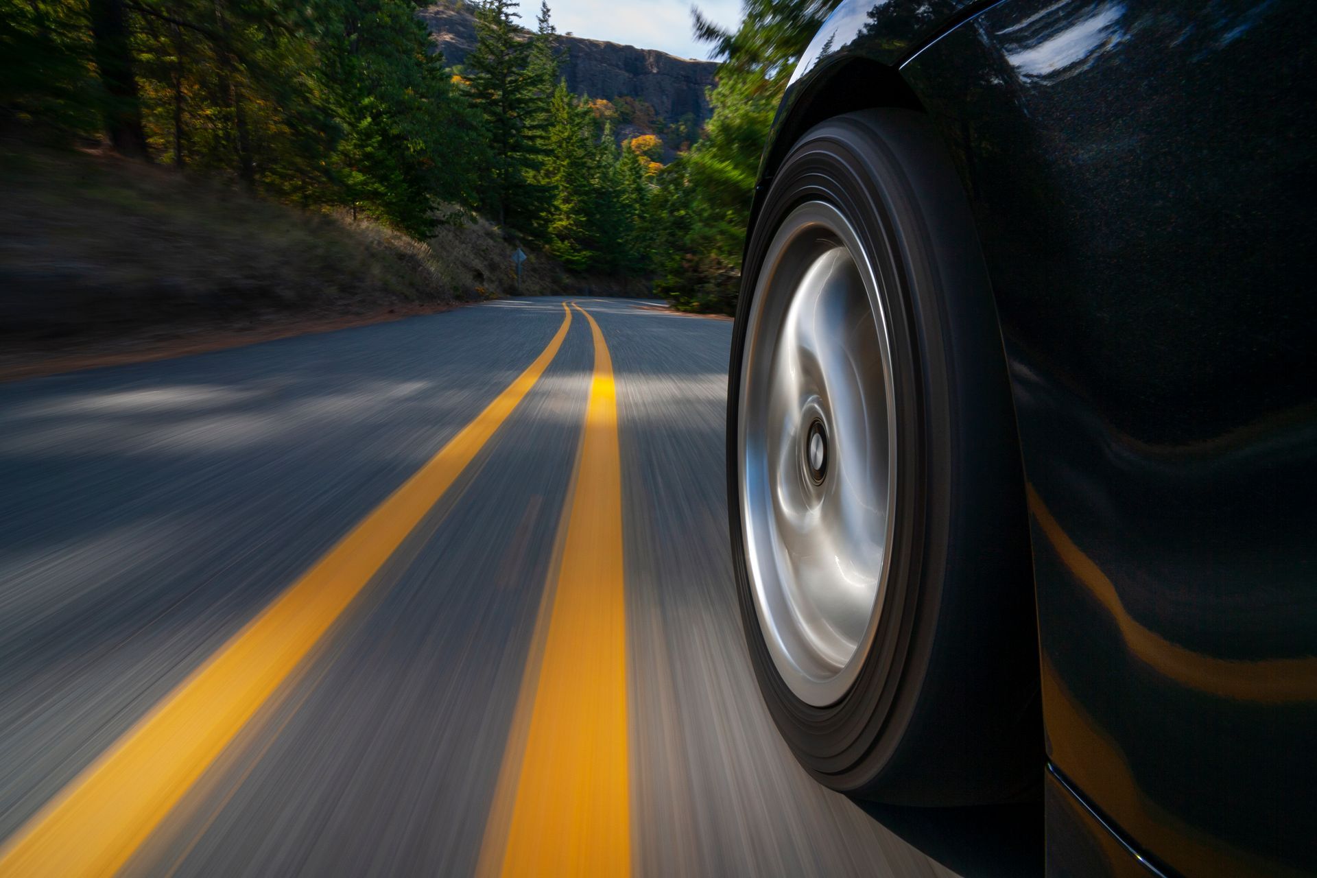 A car is driving down a road with yellow lines.