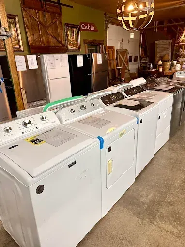 Row of white washing machines in a laundry room with wooden walls and pendant lighting
