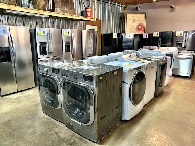 Used appliances display with rows of refrigerators, washers, and dryers in a warehouse showroom
