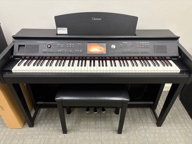 Digital piano with bench in a room, black finish and orange display panel