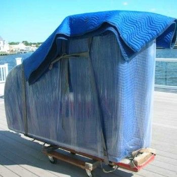Blue-tarp-covered cart on wheels beside a waterfront boardwalk