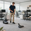 Man cleaning office carpet with a vacuum and floor scrubber in a modern workspace