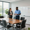 Two colleagues discussing documents in a modern conference room with a whiteboard and meeting table