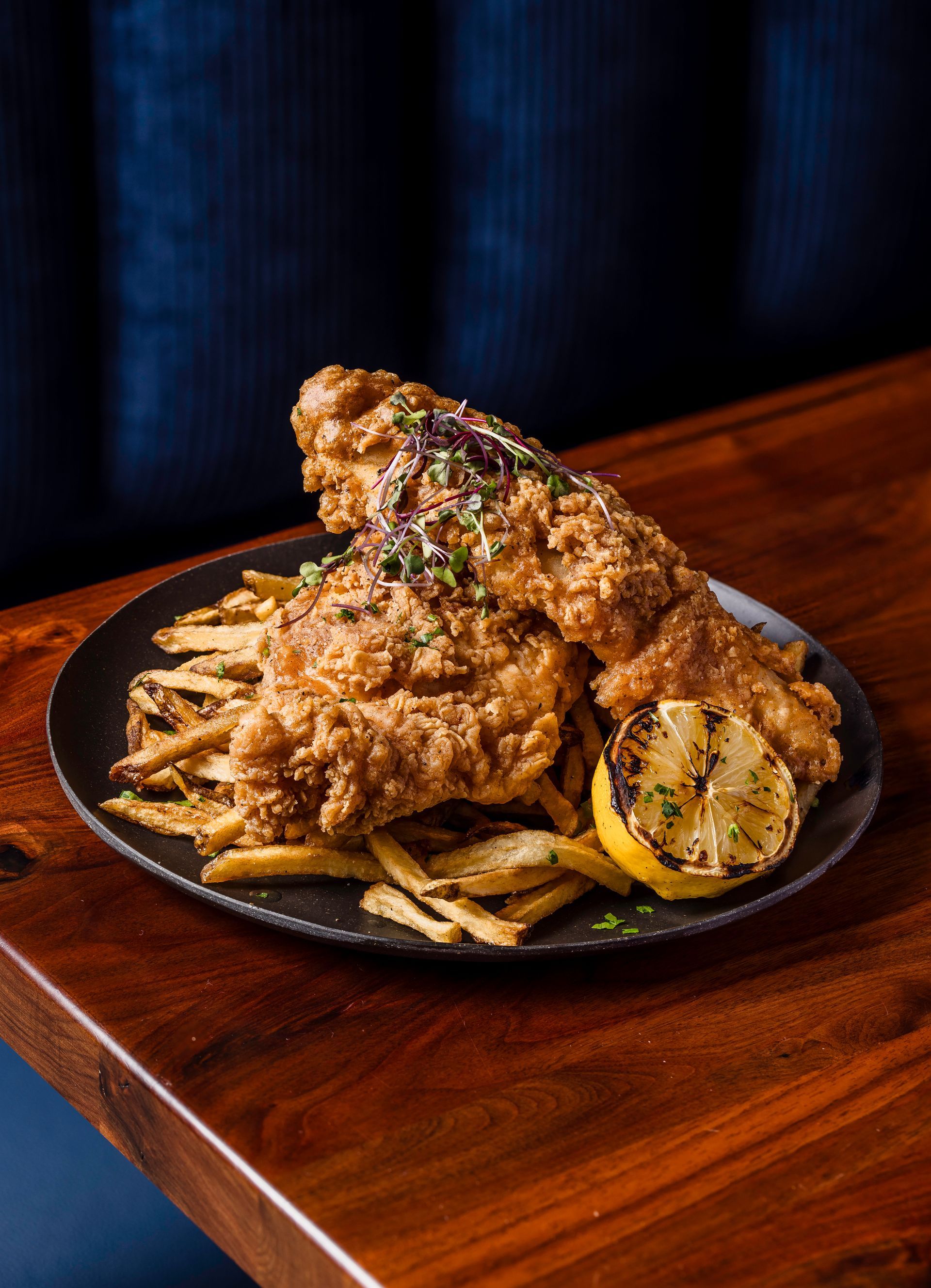 A plate of fried fish and french fries on a wooden table