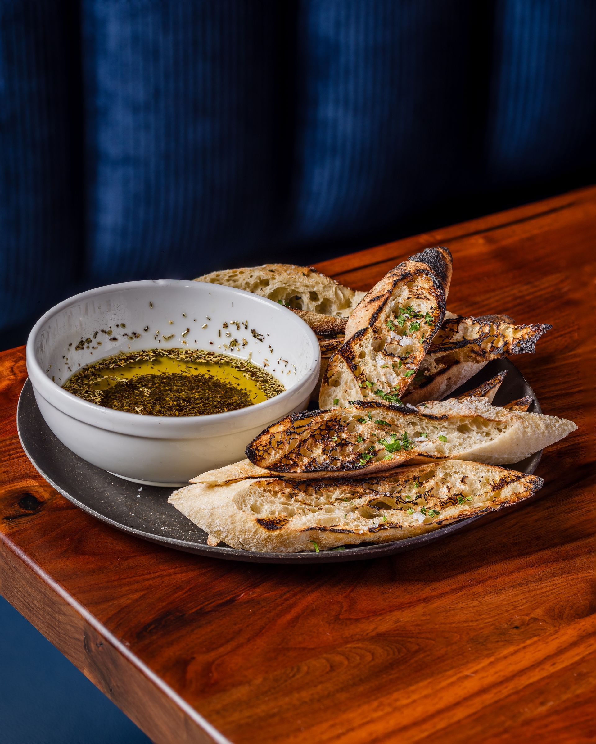 A plate of bread and a bowl of dipping sauce on a wooden table