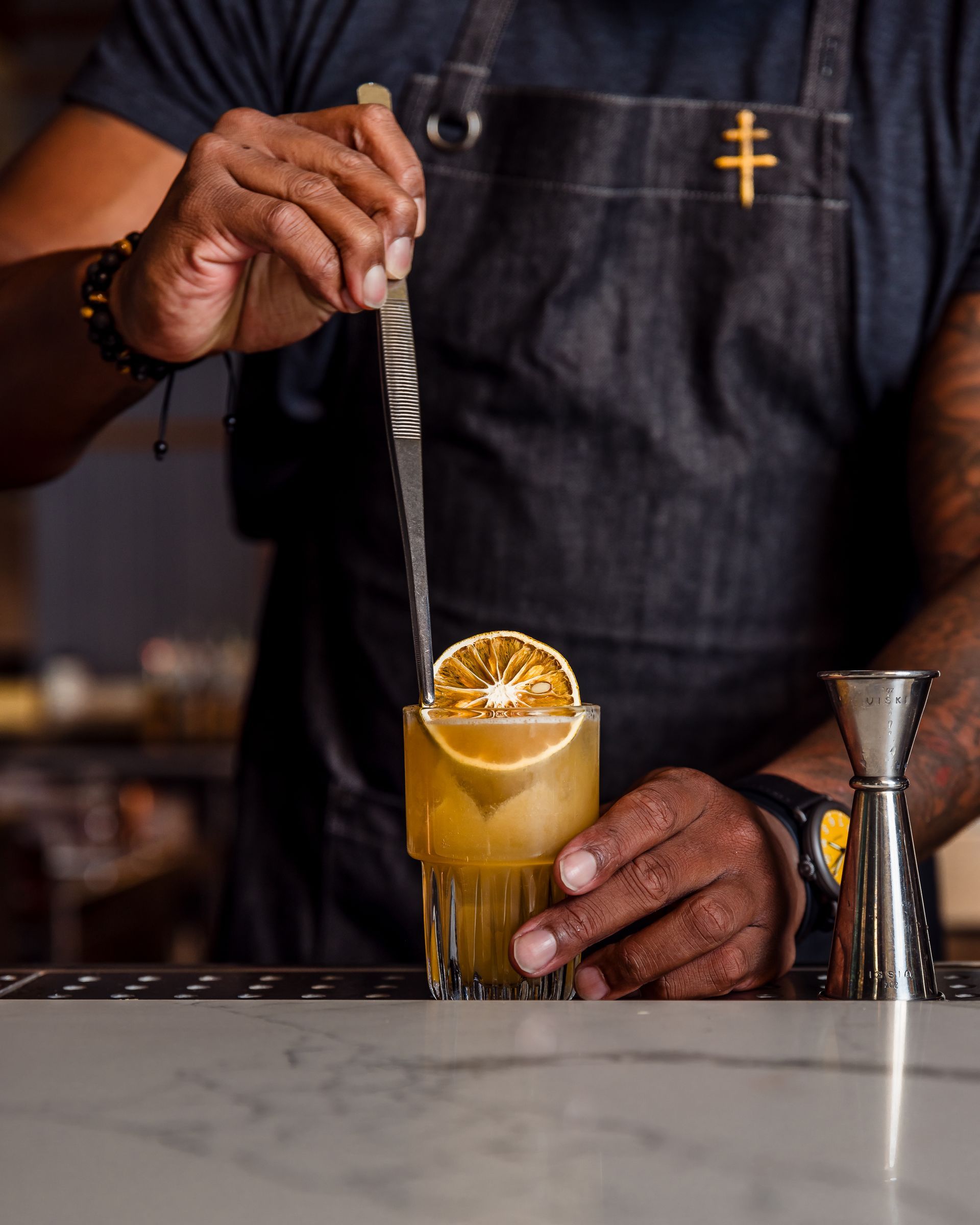 A bartender is preparing a drink with an orange slice on top