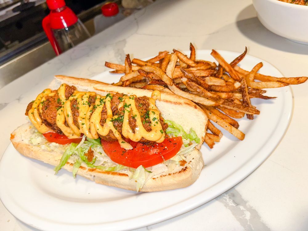 A sub sandwich with french fries on a white plate