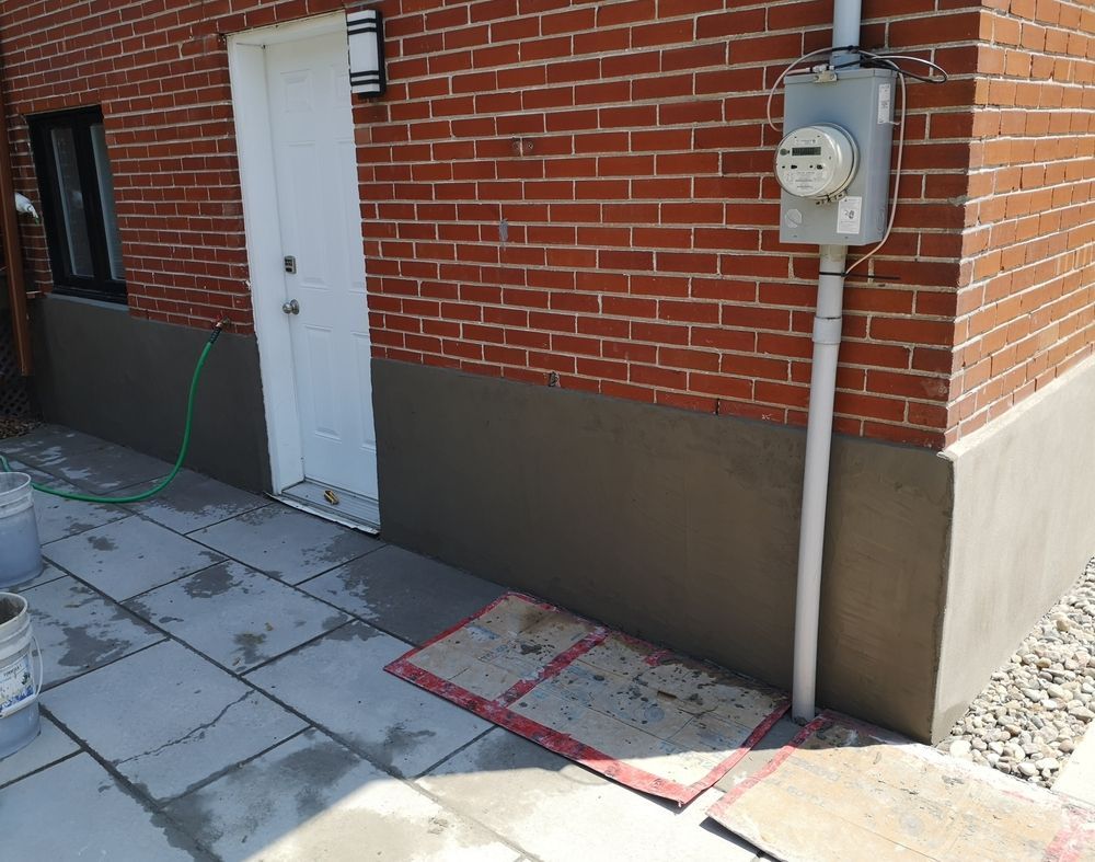 Brick building exterior with white door, utility meter, and paved walkway with marked access path
