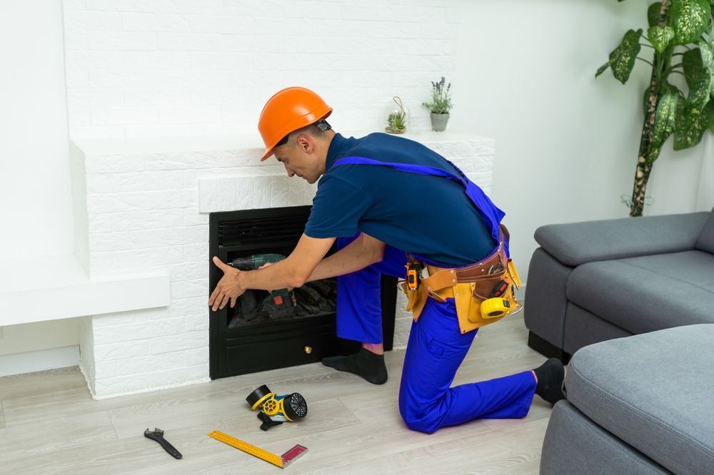 Technician in orange hard hat installing a fireplace in a living room with tools on the floor