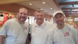 Three men are posing for a picture in a restaurant.