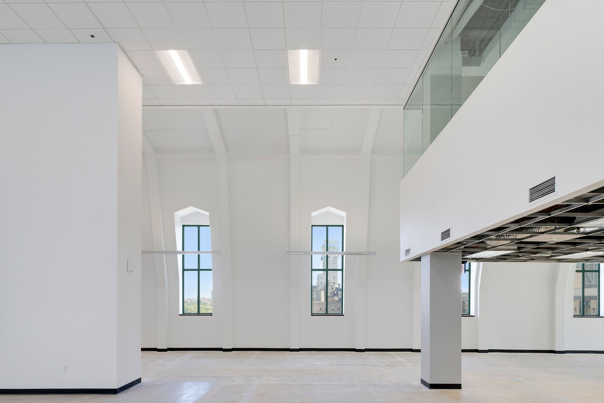 White interior space with windows, columns, and a modern ceiling.