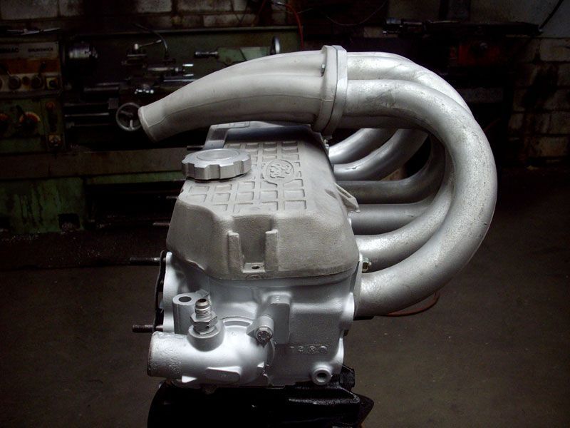 A close up of a car engine with a hose attached to it