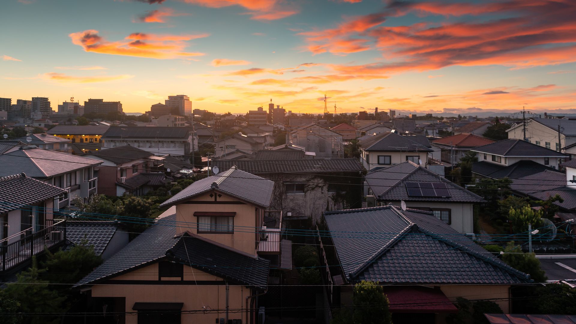 City rooftops at sunset, with an orange and pink sky.