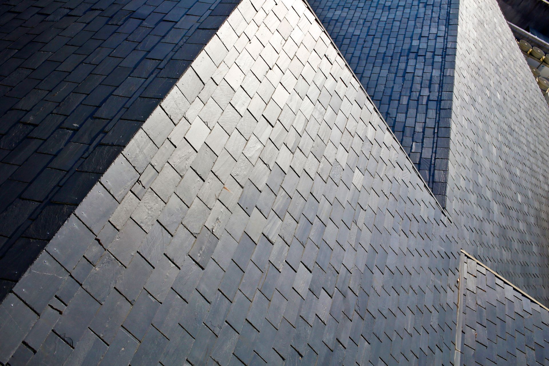 Dark gray tile roofing, close-up view from above, angled patterns.