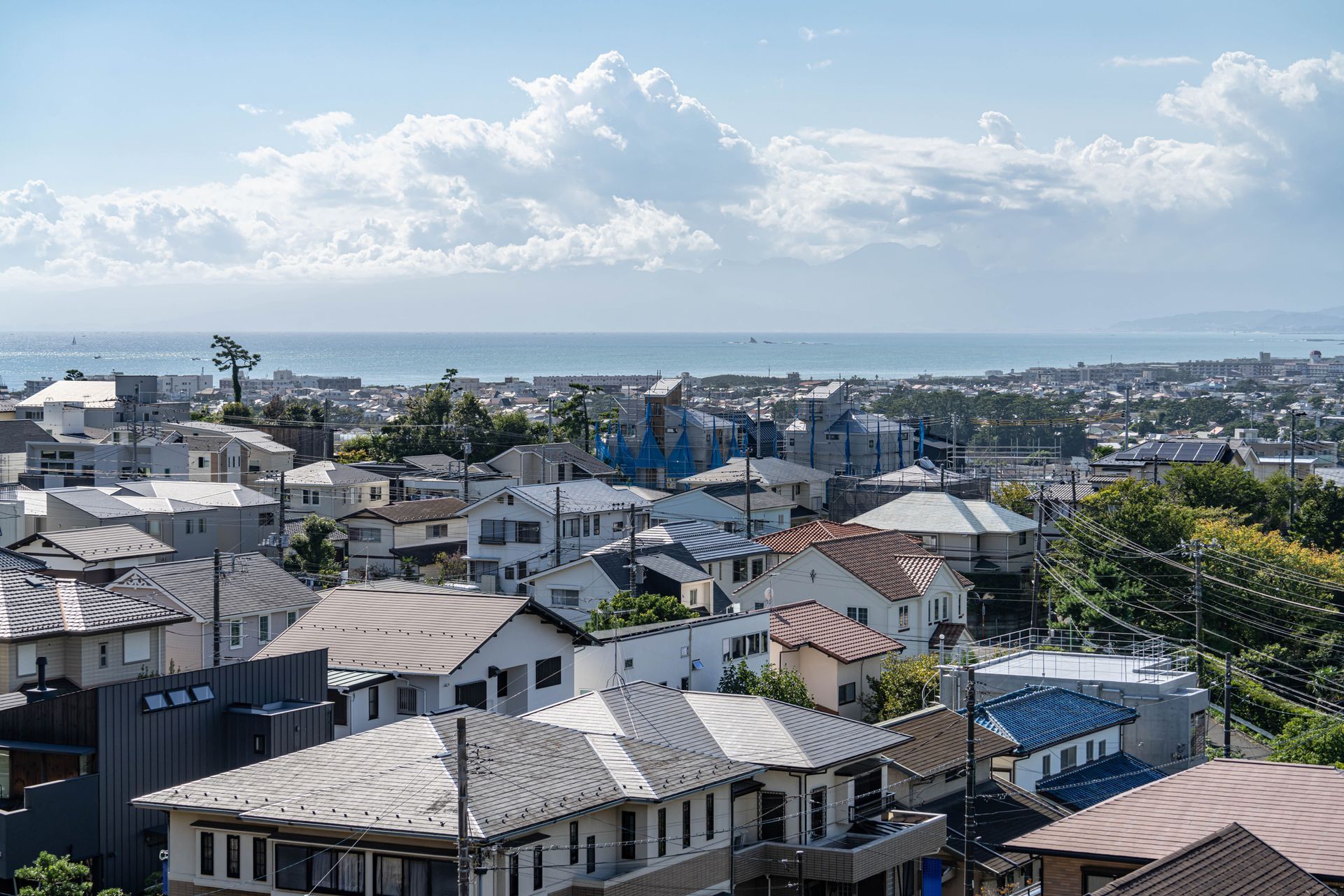 Houses clustered together overlooking a blue ocean under a partly cloudy sky.