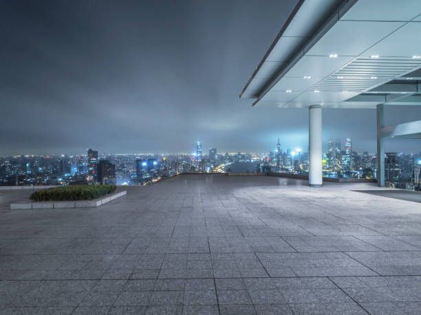 City skyline view from a rooftop patio at night, overcast sky, building columns on the right.