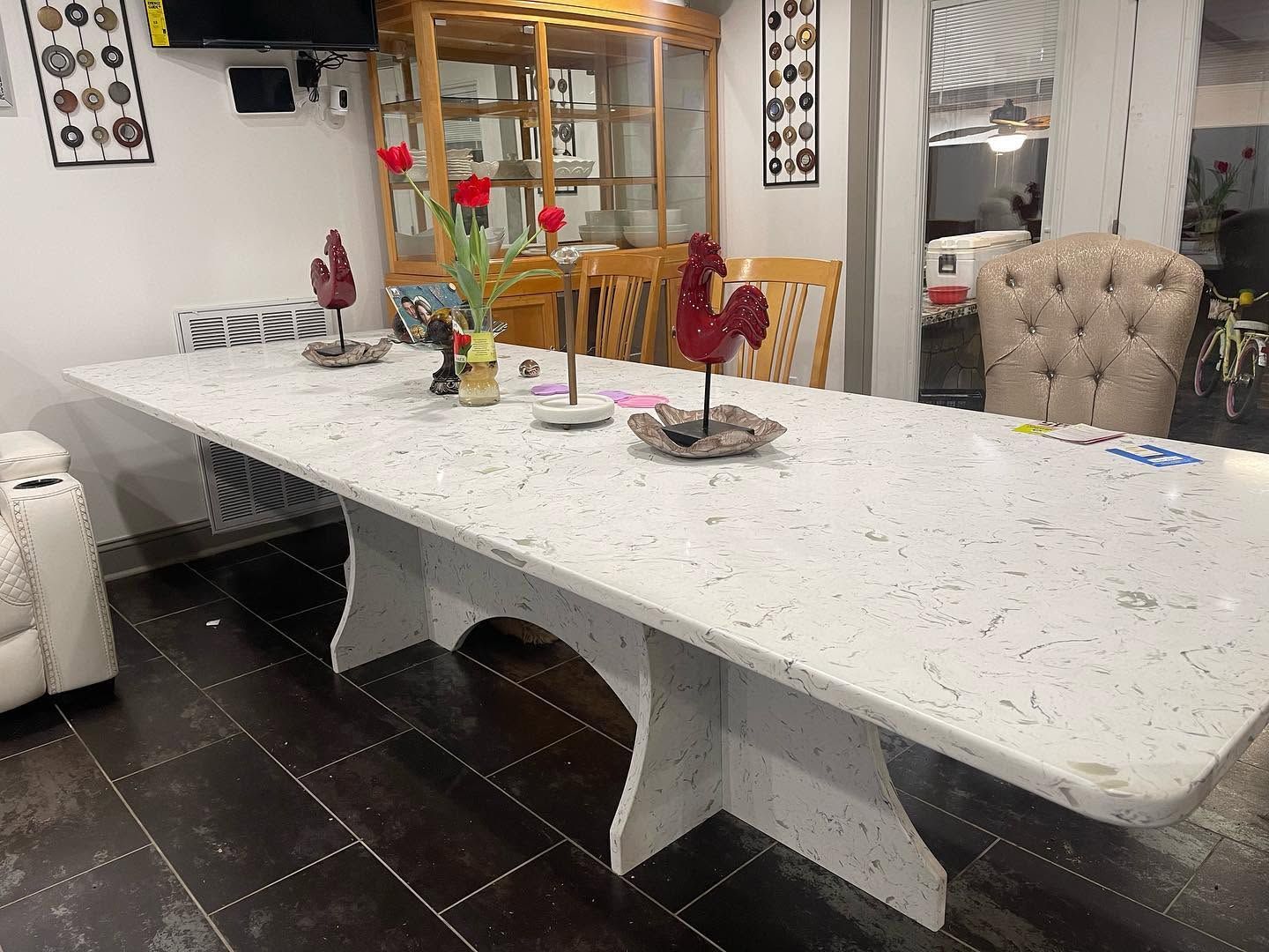 Modern dining room with a long white table, dark tile floor, and decorative centerpieces