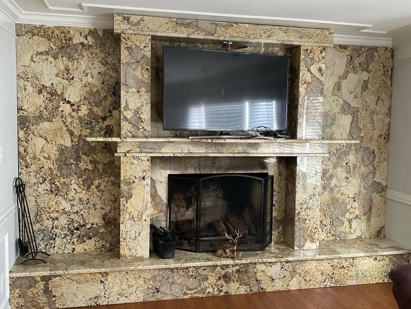 Living room fireplace with a wall-mounted TV above a speckled stone surround
