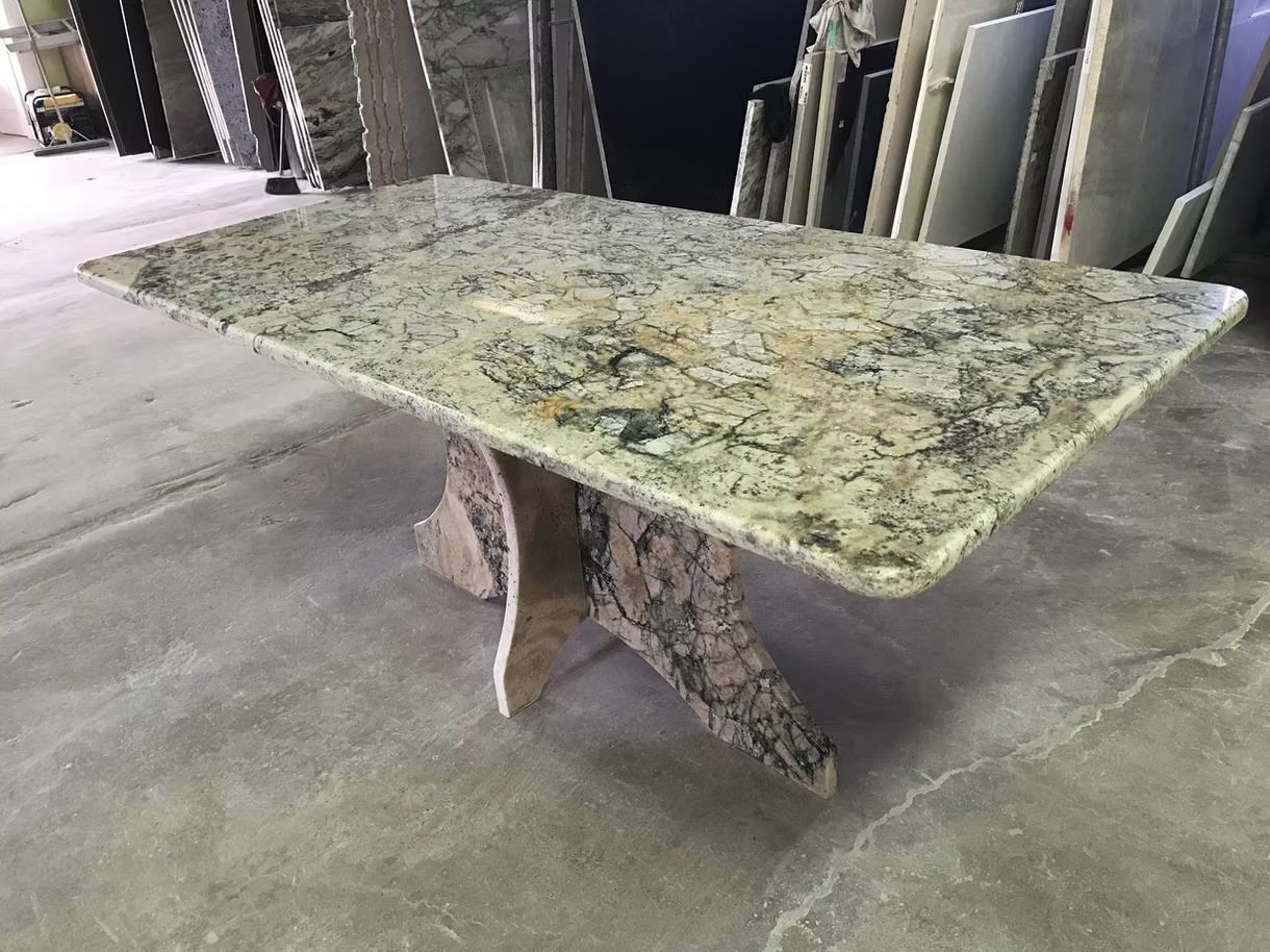 Granite-topped table with a curved pedestal base in a showroom or workshop.