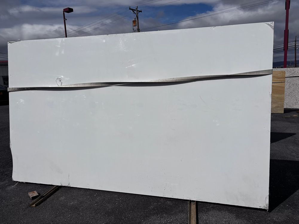 White rectangular signboard outdoors on a metal stand against a cloudy sky
